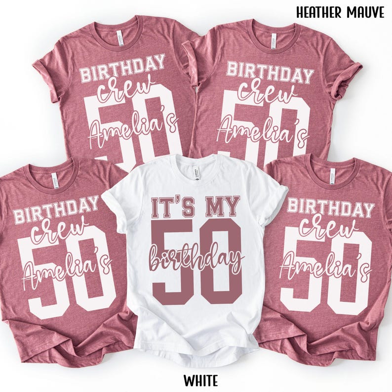 May include: Four heather mauve t-shirts and one white t-shirt. The mauve shirts feature white text reading BIRTHDAY crew, Amelia's, and a large 50. The white shirt features mauve text reading IT'S MY 50 birthday. Text HEATHER MAUVE and WHITE is visible.
