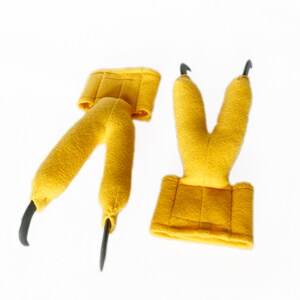 Pode incluir: Dois fantoches de m&atilde;o de feltro amarelo com garras pretas. Os fantoches s&atilde;o projetados para parecer p&eacute;s de p&aacute;ssaro.