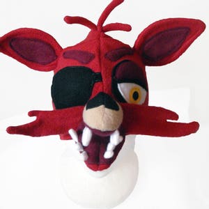 Puede incluir: M&aacute;scara de cabeza de zorro de felpa roja y negra con parche en el ojo y una sonrisa de dientes. La m&aacute;scara est&aacute; hecha de tela suave y peluda y tiene un aspecto realista.