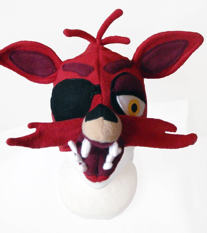 Puede incluir: M&aacute;scara de cabeza de zorro de felpa roja y negra con parche en el ojo y una sonrisa de dientes. La m&aacute;scara est&aacute; hecha de tela suave y peluda y tiene un aspecto realista.