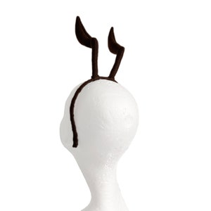 May include: A brown headband with two brown fuzzy antlers attached to it.