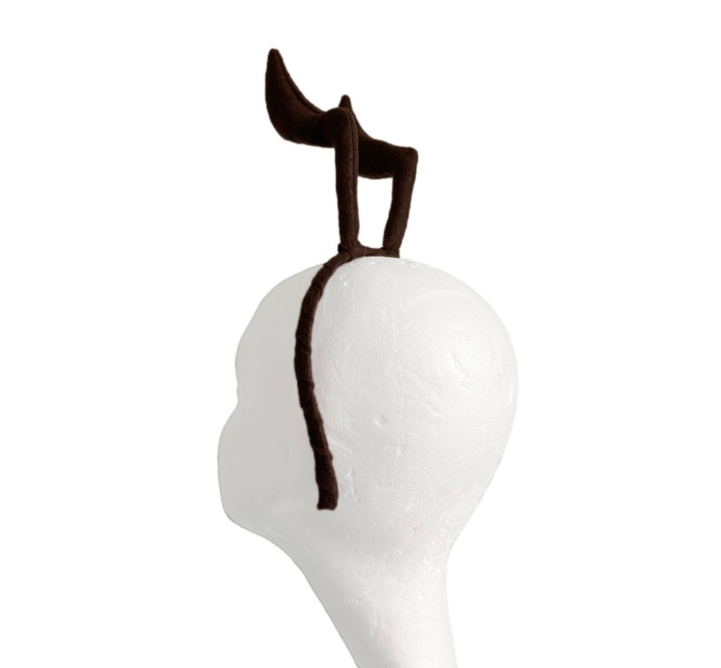 May include: A brown felt headband with two curved horns. The headband is on a white styrofoam head.