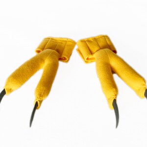 Pode incluir: Um par de fantoches de garras de p&aacute;ssaro de feltro amarelo com garras pretas.