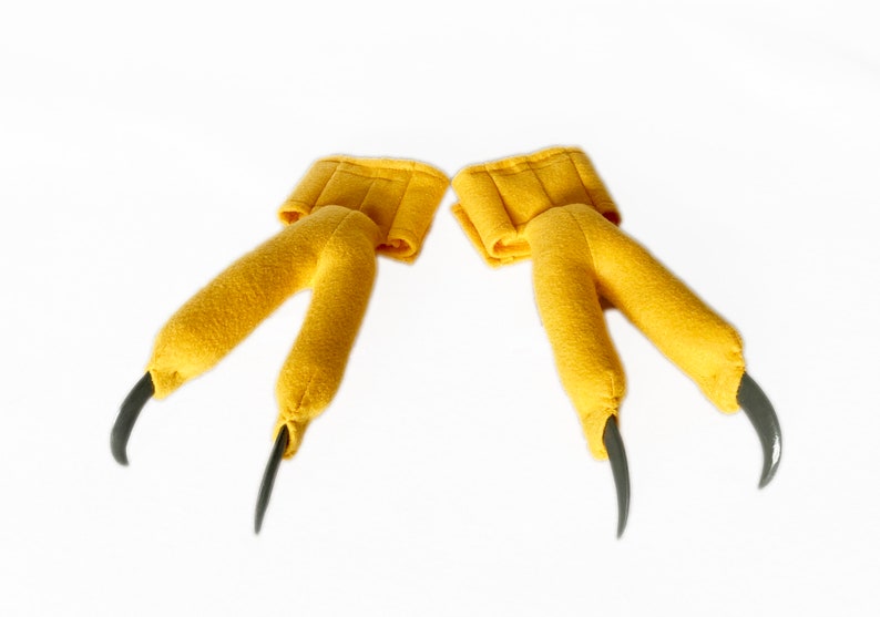 Pode incluir: Um par de fantoches de garras de p&aacute;ssaro de feltro amarelo com garras pretas.