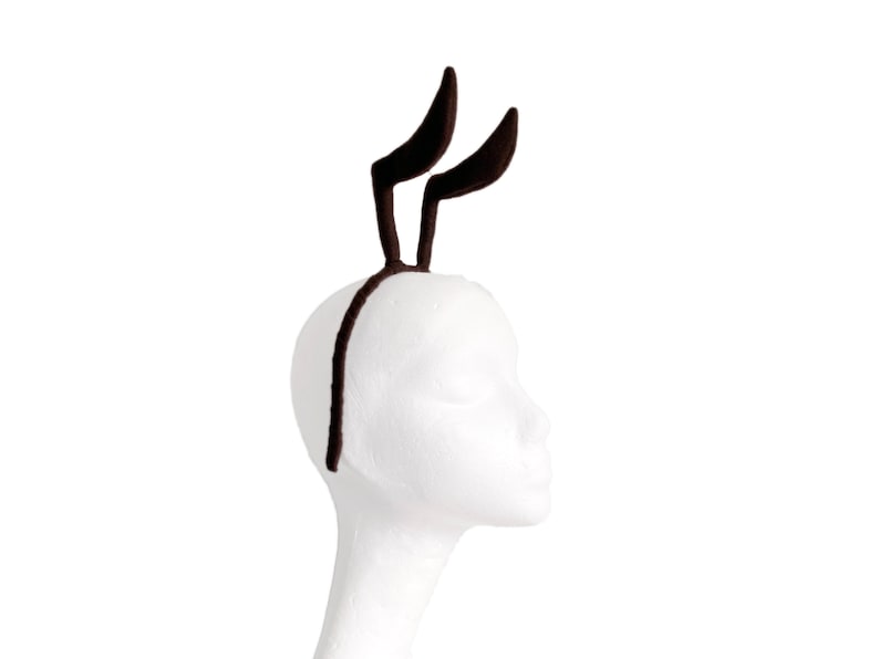 May include: A pair of brown bunny ears headband with a black headband.