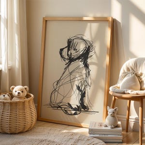 Puede incluir: Una obra de arte enmarcada con un boceto abstracto negro de un perro sobre un fondo crema. La obra de arte está en un marco de madera de color claro. La imagen se muestra en una habitación con una paleta de colores neutros.