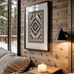 Peut inclure: Un cadre noir contient une impression géométrique en noir et blanc sur un mur en bois. L'impression présente un motif de diamant central avec un motif de bordure. Une applique noire et une bougie allumée créent une ambiance chaleureuse.