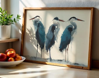 May include: A framed watercolour print depicting three blue herons. The birds have long legs and beaks, set against a neutral background. The artwork is encased in a natural wood frame, adding a touch of rustic charm to the piece.