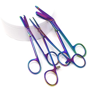 May include: Set of four rainbow-colored surgical scissors with the name "Ronaldo" engraved on each. The scissors are arranged on a white surface.