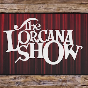 May include: Rectangular doormat featuring the text "The Orcana Show" in white, set against a red curtain backdrop. The mat has a black border and is displayed on a wooden surface.