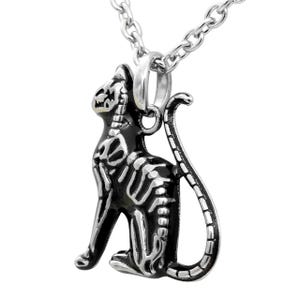 May include: A silver chain necklace with a black and silver cat skeleton pendant. The pendant is detailed with a skeletal design and has a shiny finish.