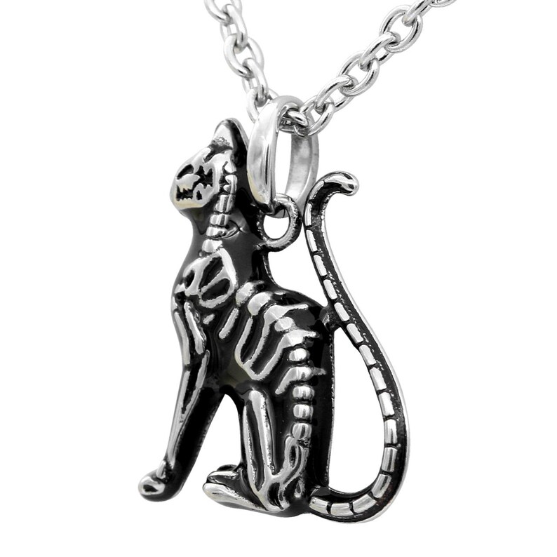 May include: A silver chain necklace with a black and silver cat skeleton pendant. The pendant is detailed with a skeletal design and has a shiny finish.