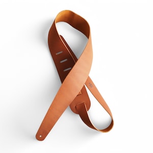 May include: A brown leather guitar strap with adjustable length and a simple design.