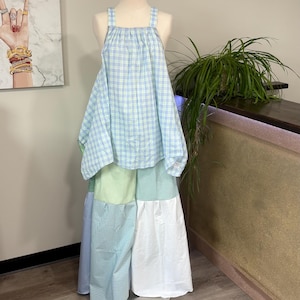 May include: A sleeveless top and wide-leg pants set. The top features a light blue and lime green plaid pattern with thick straps. The pants are constructed from patchwork panels of solid light green, white, and light blue gingham fabric.