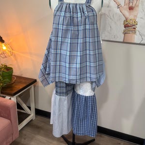 Puede incluir: Un conjunto de top sin mangas y pantalón de pierna ancha con estampado de cuadros azules y blancos. El top tiene un escote cuadrado con tela fruncida, mientras que el pantalón está confeccionado con un patchwork de telas a cuadros y rayas.