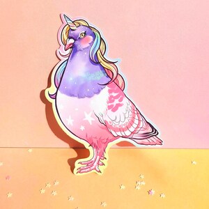 May include: A whimsical sticker featuring a pigeon with a unicorn horn and rainbow-colored mane. The bird is primarily purple and pink, with white stars on its chest and a yellow outline. The background is a gradient of pink and yellow.
