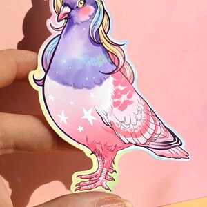 May include: A sticker featuring a whimsical illustration of a pigeon with a unicorn horn and rainbow-colored mane. The bird's body transitions from purple to pink, adorned with white stars. The sticker has a yellow outline.