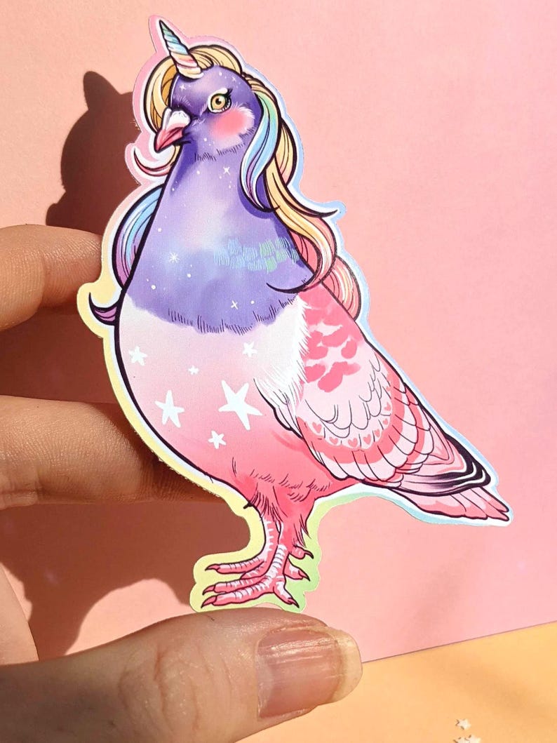 May include: A sticker featuring a whimsical illustration of a pigeon with a unicorn horn and rainbow-colored mane. The bird's body transitions from purple to pink, adorned with white stars. The sticker has a yellow outline.