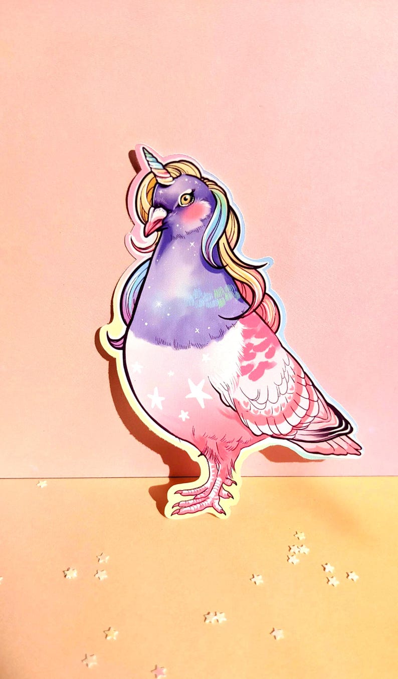 May include: A sticker featuring a whimsical illustration of a pigeon with a unicorn horn and flowing rainbow hair. The bird has a purple head and chest, transitioning to pink feathers with star accents. The background is a gradient of pink and peach.