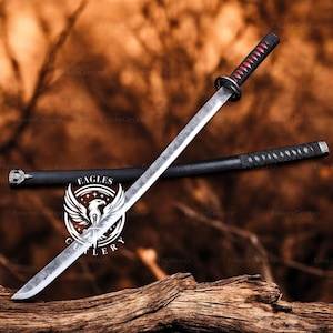 May include: A katana sword with a silver blade and a black handle with red accents. The sword is displayed on a wooden surface with its black scabbard. The logo "EAGLES CUTLERY" is visible.