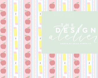 May include: A repeating pattern of red apples and yellow pencils on a striped background of pink, blue, and white. The design includes the text "THE DESIGN atelier" on a light green rectangle.