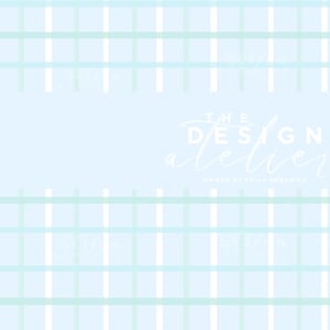 May include: A pale blue background featuring a grid pattern in white and light green. The text "THE DESIGN atelier" is in white script, with "OWNED BY ERIKA KENDRICK" below it.