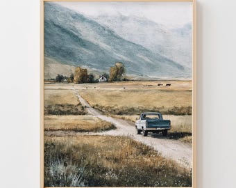 Könnte beinhalten: Aquarell-Kunstdruck mit einer ländlichen Szene mit einer unbefestigten Straße, einem blauen Pickup-Truck und einer fernen Bergkette. Das Kunstwerk hat eine neutrale Farbpalette mit Braun-, Grün- und Blautönen und ist in einem hellen Holzrahmen gerahmt.