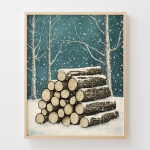 May include: A framed print depicts a winter scene with a stack of snow-covered logs in the foreground. The logs are brown and beige, with visible wood grain. The background features bare trees and a teal sky with falling snowflakes.