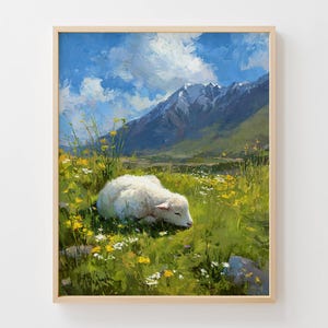 Puede incluir: Una pintura de paisaje enmarcada representa un cordero blanco descansando en un campo de flores silvestres. El fondo presenta montañas bajo un cielo azul con nubes blancas. La obra de arte está en un marco de madera natural.