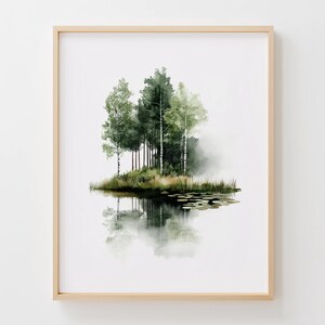 Pode incluir: Uma impressão em aquarela emoldurada de uma paisagem serena. A obra de arte retrata um grupo de árvores verdes em uma pequena ilha, refletidas na água calma abaixo. A pintura tem uma qualidade suave e etérea, com verdes e brancos suaves.