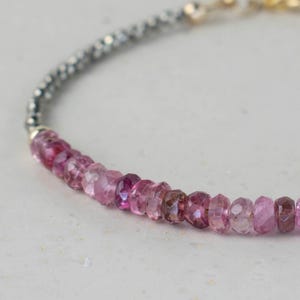 May include: A delicate bracelet featuring a gradient of pink and purple gemstones, interspersed with silver beads.