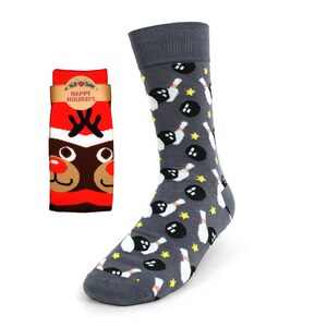 May include: A pair of socks with a bowling ball and pin pattern on one sock and a reindeer face on the other sock. The socks are gray with yellow, white, and black accents. The reindeer sock has a red background with a white hat and a brown face. The tag on the reindeer sock says "Happy Holidays".