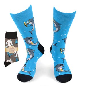 May include: A pair of blue socks with a pattern of sharks wearing sunglasses. The socks have a black toe and heel.