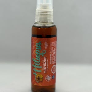 May include: A brown liquid spray bottle with a clear cap. The label reads "Heliopsis Chilcuague Concentrado" with a flower graphic. The bottle contains 60ml of liquid.