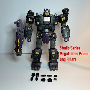 May include: A black and purple action figure of a robot with yellow accents. The figure has multiple points of articulation and comes with additional black pieces. Text on the image reads "Studio Series Megatronus Prime Gap Fillers."