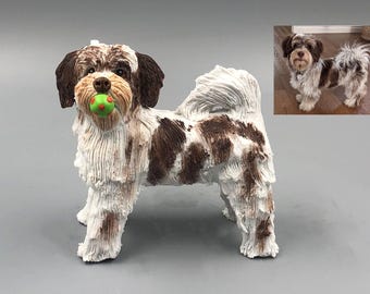 May include: A white and brown dog figurine with a green ball in its mouth. The figurine is standing on a gray surface.