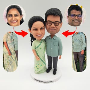 Może przedstawiać: Spersonalizowana figurka bobblehead pary, ze szczegółowymi twarzami i ubraniami. Kobieta ma na sobie jasnozielone sari, a mężczyzna jasnozieloną koszulę zapinaną na guziki i szare spodnie. Na podstawie napis "Happy 25th Anniversary."