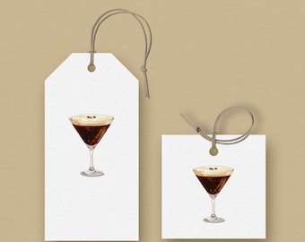 Può includere: Due etichette regalo bianche con un'illustrazione ad acquerello di un espresso martini. Il cocktail è in un bicchiere a stelo, con una bevanda marrone scuro e una parte superiore schiumosa. Le etichette hanno un cordino per appenderle.