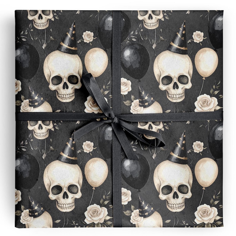 May include: Gift wrap featuring a repeating pattern of skulls wearing party hats, black balloons, and cream-colored roses on a dark background. The gift is tied with a black ribbon and bow.