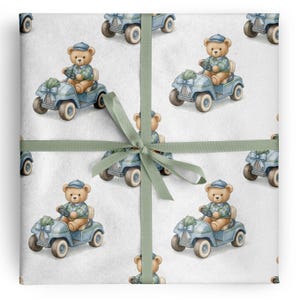 Puede incluir: Papel de regalo con un patrón repetitivo de osos de peluche de color marrón claro con gorras azules y jerséis verdes, cada uno conduciendo un carrito de golf azul claro decorado con un lazo azul. El papel está atado con una cinta verde salvia.