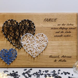 Könnte beinhalten: Holzschilder mit drei String-Art-Herzen in Schwarz, Weiß und Blau. Das Schild hat den Text "FAMILIE... wo das Leben seinen Anfang nimmt und die Liebe niemals endet... Yannick, Adriana & Malte" eingraviert.