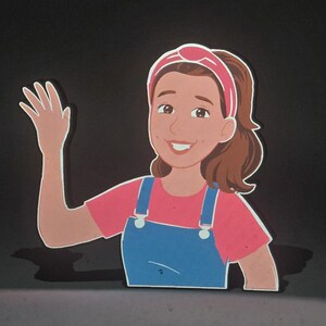 May include: A colorful cutout of a cartoon woman waving. She wears a pink shirt, blue overalls, and a pink headband. Her brown hair is pulled back in a ponytail. The background is black.