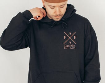 May include: Black hooded sweatshirt with a pink graphic design featuring a cross with the letters "A P P A" and the text "Danielle EST. 2025".