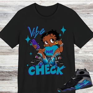 Puede incluir: Camiseta negra con un personaje de dibujos animados sosteniendo un teléfono, con las palabras "Vibe Check" en azul y morado. El personaje lleva una camiseta azul con la palabra "DOPE" y vaqueros azules. Un par de zapatillas negras y azules están en la imagen.