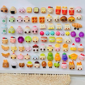 May include: A collection of miniature food charms, including cakes, pastries, fruits, and vegetables. The charms are made of polymer clay and are painted in bright, vibrant colors.