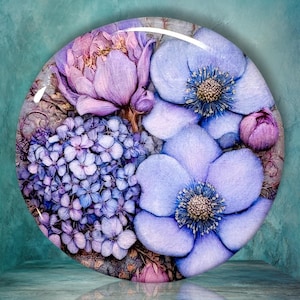 May include: A circular decorative piece featuring a detailed floral arrangement in shades of purple, lavender, and blue. The design includes clusters of small hydrangea-like blossoms, large open-petaled flowers with textured centers, and buds.