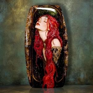 May include: A rectangular decorative plaque featuring a glossy, resin-coated illustration of a person with long, flowing red hair and closed eyes. The figure is framed by an ornate, dark, and metallic-toned border with gold-colored accents.