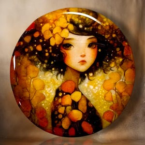 May include: A circular decorative plate featuring a stylized illustration of a person with dark hair surrounded by vibrant yellow and orange autumn leaves. The artwork uses a warm color palette with golden highlights and a glossy finish.