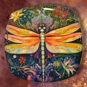 May include: A square decorative tile featuring a detailed illustration of a dragonfly with vibrant orange and yellow wings. The dragonfly is centered against a dark, intricate background filled with colorful floral patterns, green foliage, and small circular accents.