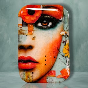 May include: A rectangular glass plaque featuring a vibrant artistic portrait of a face with bright orange and red tones. The design includes a large orange flower near the eye, bold red lips, and delicate yellow and white floral accents on the side.